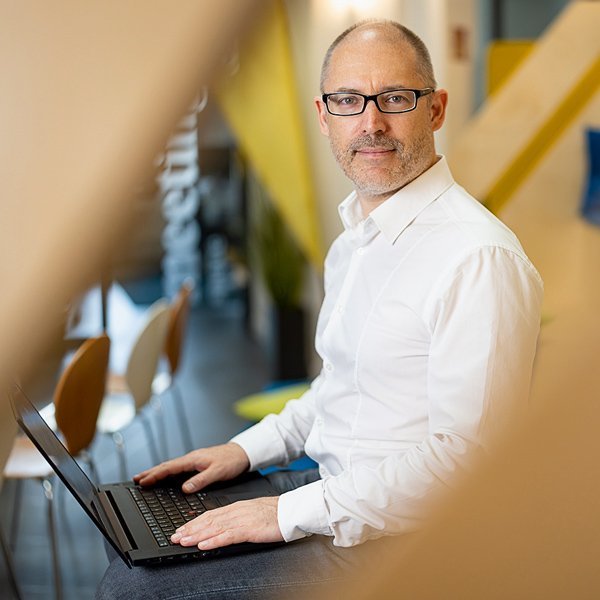 Ein Mann mit Brille sitzt vor einem Notebook. 